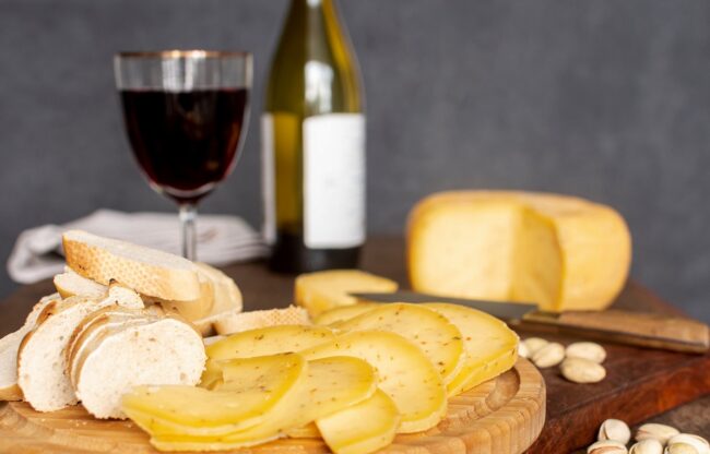 cheese-wine-FP Cheese board with bottle of wine and glass of wine in the background.