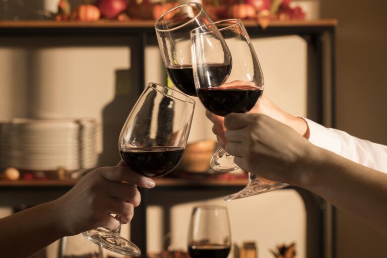 Closeup of tree hands toasting with red wine illustrates blog "Tannins and Wine: What You Need To Know"