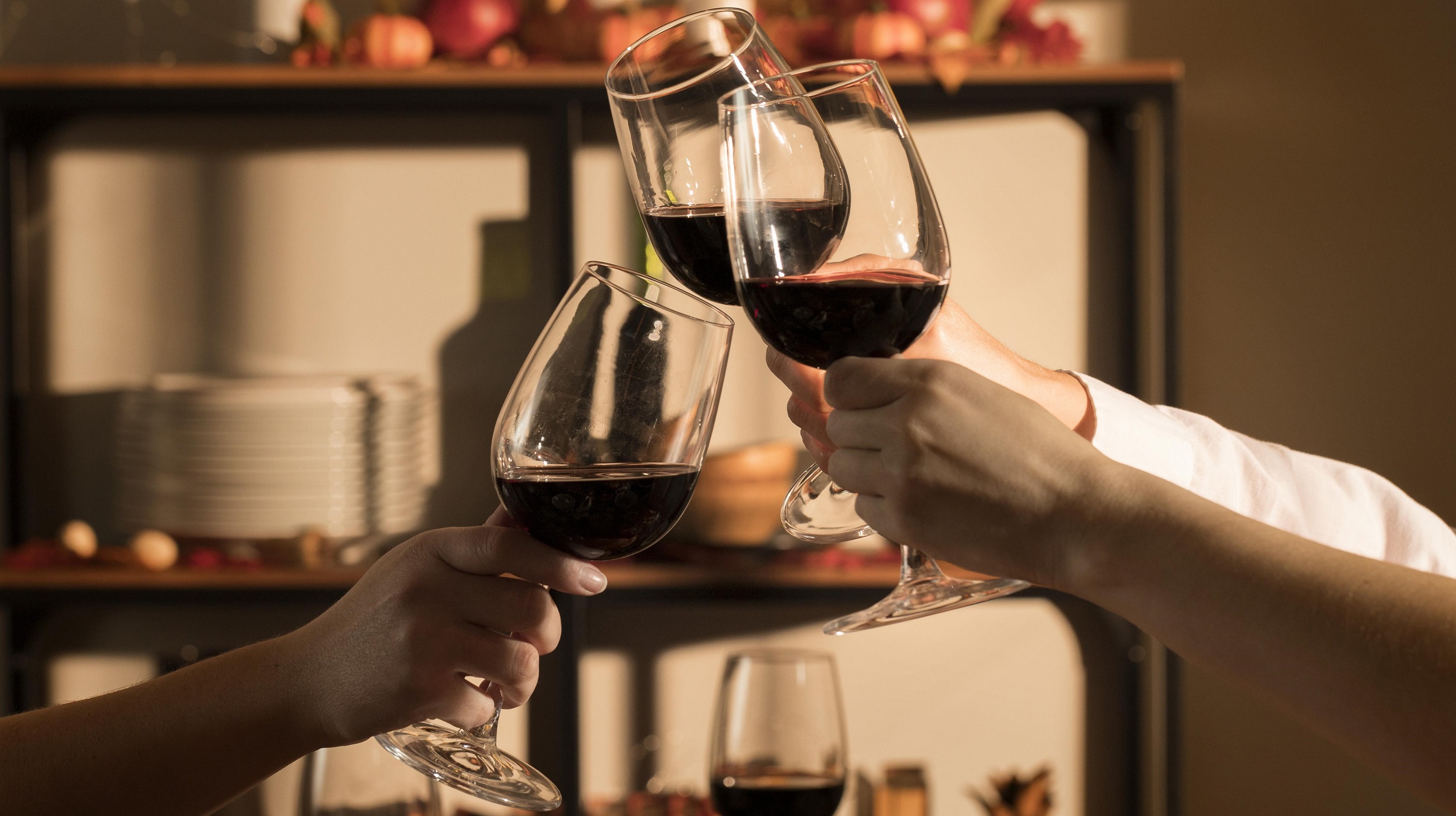 Closeup of tree hands toasting with red wine illustrates blog "Tannins and Wine: What You Need To Know"