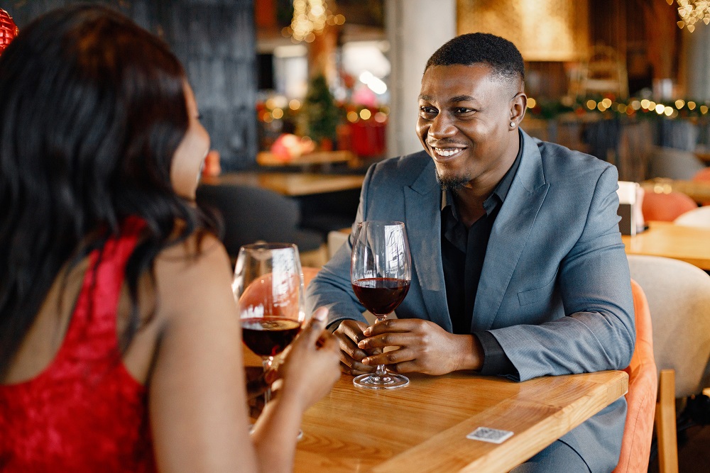 Romantic black couple sitting at restaurant wearing elegant clot Couple drinking wine at Valentine's dinner