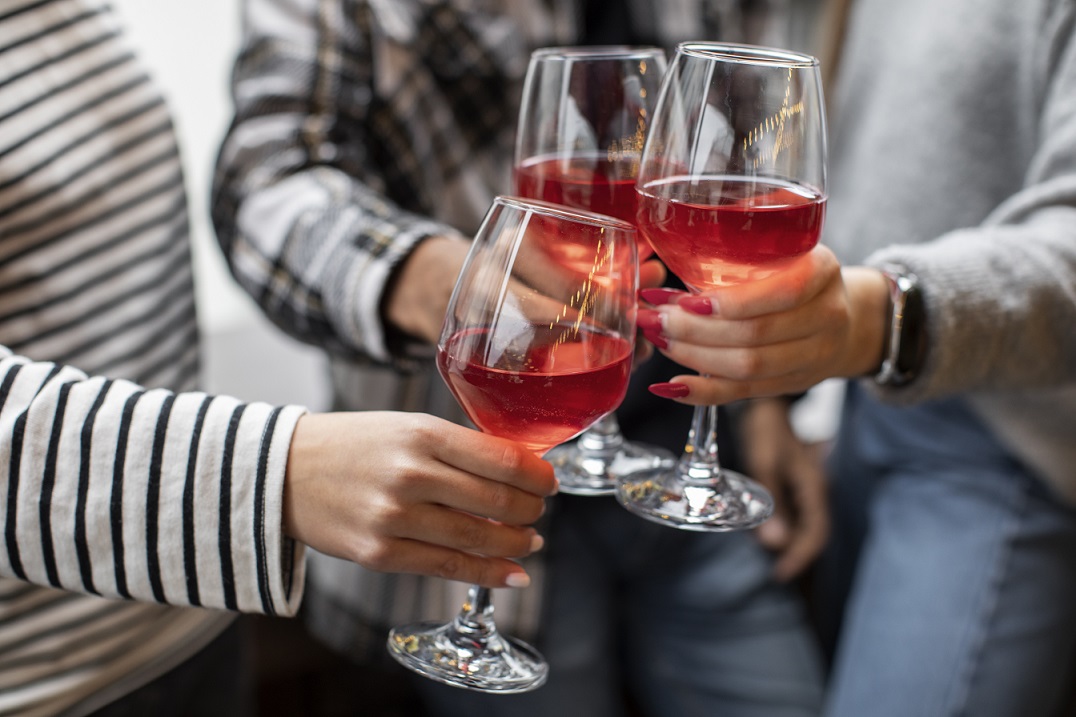 rose-wine-fp Closeup of three people making a toast with glasses of rose wine.