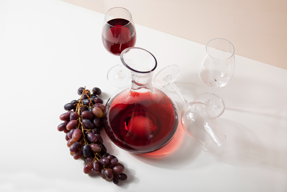 A carafe and glass of red wine with grapes
