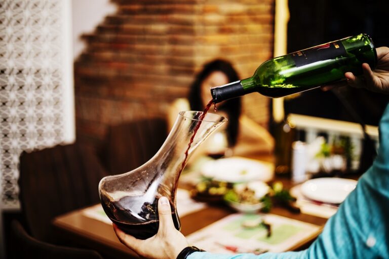 Pouring Wine at Dinner Person pouring bottle of wine into a decanter illustrates blog "A Beginner's Guide to Italian Wine"