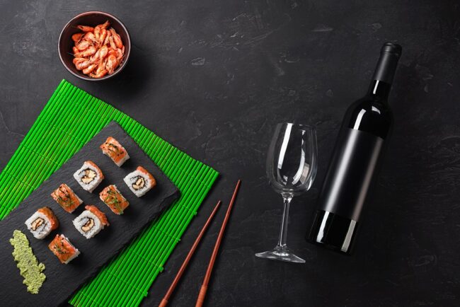 Set of sushi and maki with a bottle of wine on stone table. Top view with copy space Sushi with wine glass and bottle of red wine.
