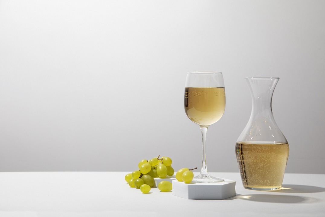 Glass of white wine with decanter and grapes illustrates blog "Does White Wine Have Tannins?"